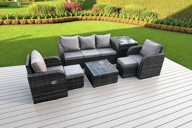The seven-seater dark grey rattan garden furniture set includes reclining chairs, footstools and two tables.